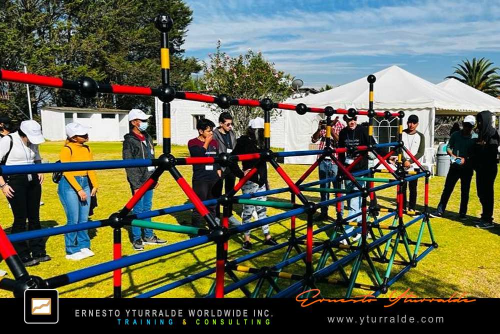 Building Bridges: Colaboradores construyendo puentes simbólicos que representan confianza y trabajo en equipo en la dinámica Building Bridges – Construyendo Puentes